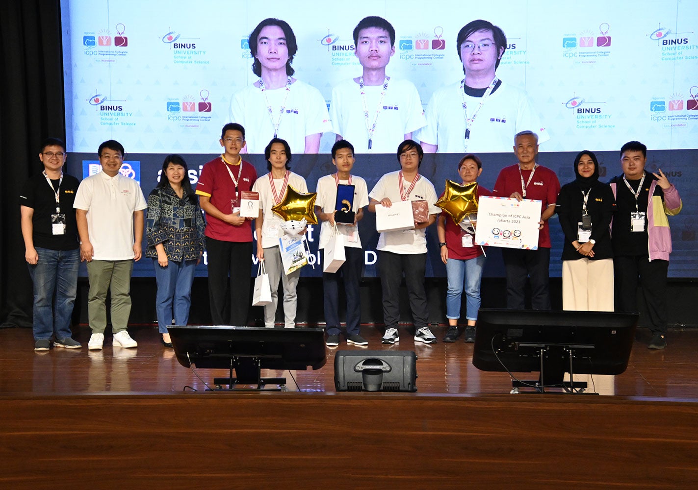 NUS Computing Associate Professor Steven Halim (fourth from left) and Associate Professor Tan Sun Teck (third from right) poses with the three Team absinthe members (centre) in white T-shirts, at ICPC Asia Jakarta Regional Contest. Team absinthe (from L to R): Nyamdavaa Amar, Bui Hong Duc, and Rama Aryasuta Pangestu.