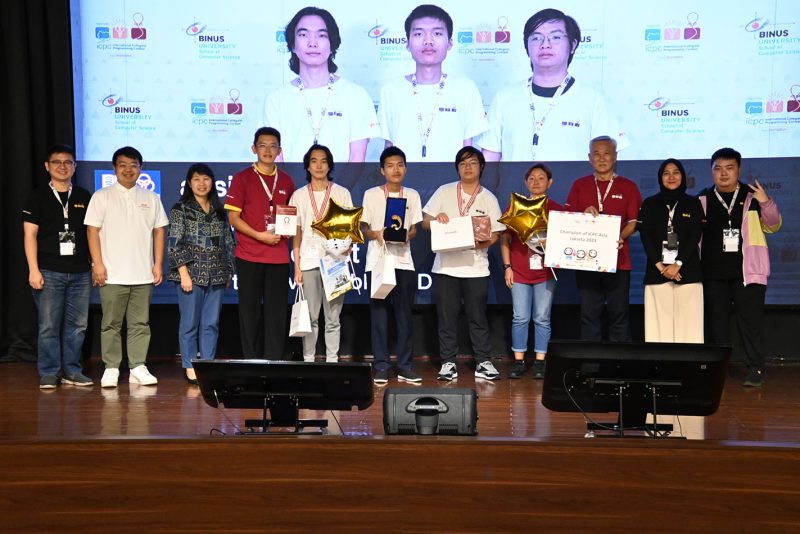 NUS Computing Associate Professor Steven Halim (fourth from left) and Associate Professor Tan Sun Teck (third from right) poses with the three Team absinthe members (centre) in white T-shirts, at ICPC Asia Jakarta Regional Contest. Team absinthe (from L to R): Nyamdavaa Amar, Bui Hong Duc, and Rama Aryasuta Pangestu.